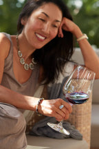 Woman smiling while holding a glass of 2020 HALL Eighteen Seventy-Three Cabernet Sauvignon