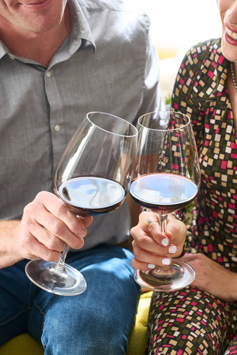 Smiling couple toasting with glasses of 2023 HALL Craig's Cabernet Sauvignon